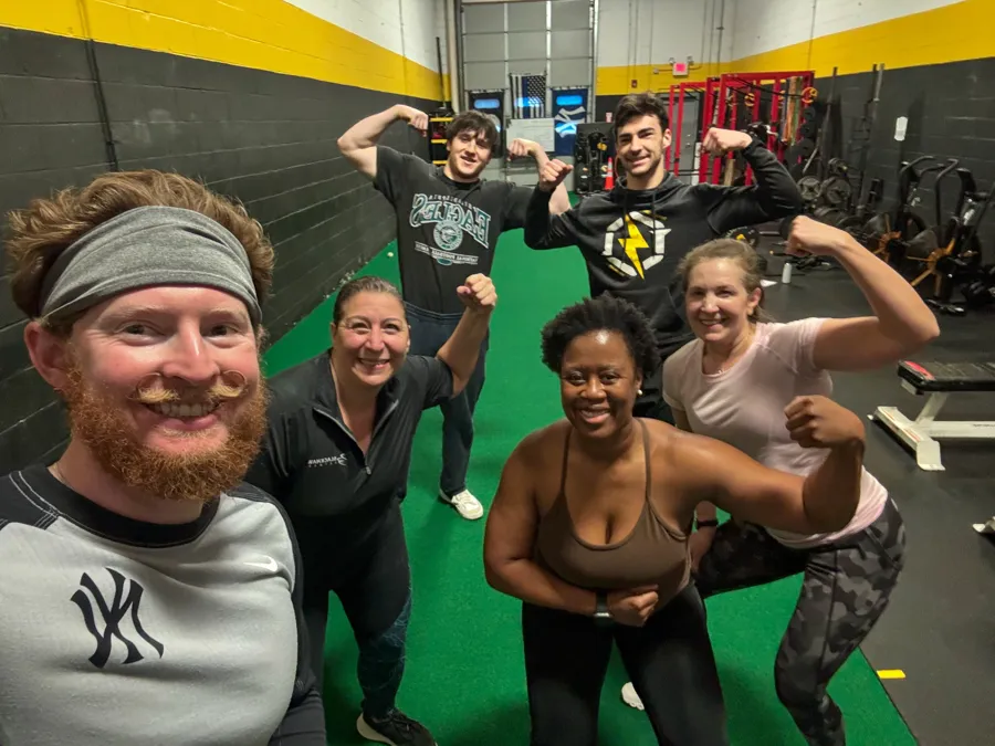 Adult personal training members celebrating a workout with coach Connor