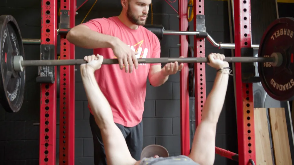 TNL coach Shawn Allen supporting an athlete during a strength session